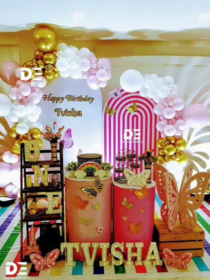 A modern and chic butterfly theme for Tvisha's first birthday. The setup includes stylish arch backdrops, gold and pink balloons, and elegant butterfly cutouts for a sophisticated look.