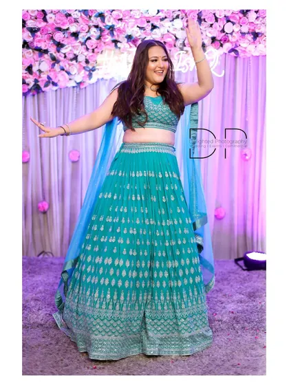 The bride-to-be shows off her dance moves in a vibrant turquoise lehenga, capturing the fun and celebratory atmosphere of the engagement party.