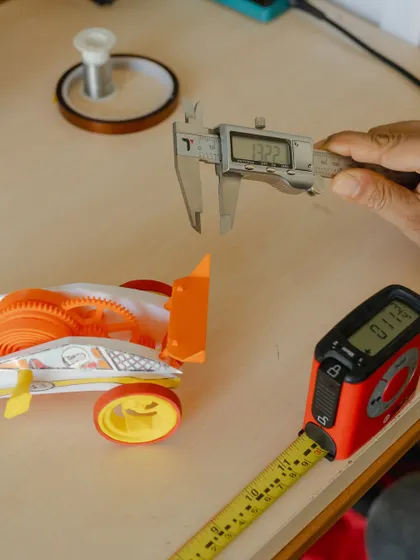 The components of our DIY 3D Printed Wind-Up Car Kit, including a vernier caliper for precise measurements. This kit teaches mechanical principles from the ground up.