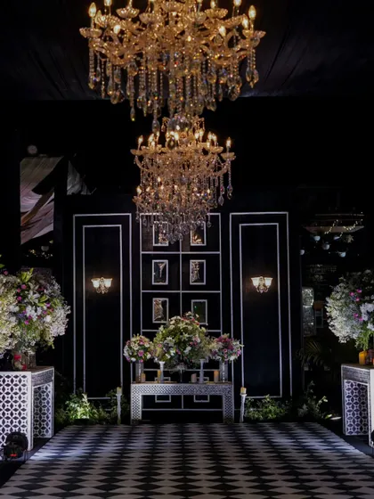 The stunning checkered dance floor is ready for a night of celebration, perfectly framed by opulent chandeliers and elegant floral decor.