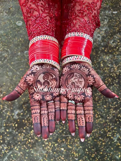 The beautiful dark stain of a Karwachauth mehndi, perfectly complemented by red bangles. This design features traditional portraits for the festival.