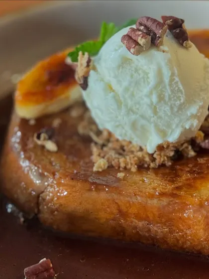A close-up of the Pain Perdu, topped with vanilla ice cream, toasted pecans, and caramelized banana.