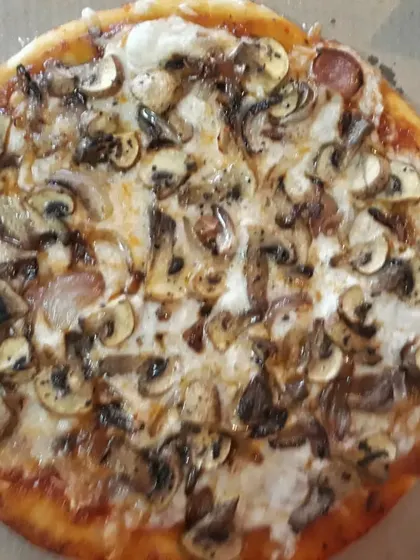 A gluten-free pizza with a generous topping of caramelized onions, mushrooms, and my special in-house vegan cheese.