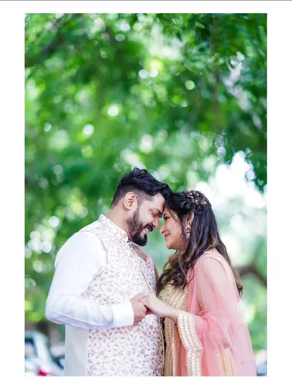 A tender moment between a bride and groom, framed by the soft green foliage. This is a classic wedding portrait that focuses on the gentle connection and happiness of the day.