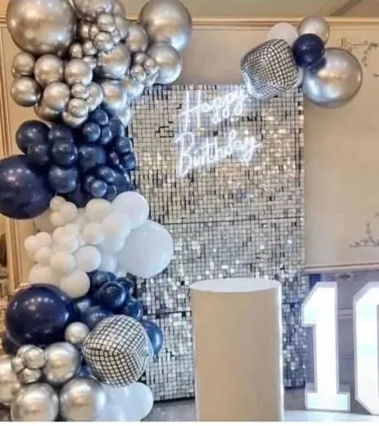 A 10th birthday party with a silver sequin wall. The decoration features a balloon garland in navy blue and silver, with disco ball accents and a marquee number '10'.