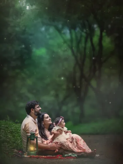 A family sitting together in the woods as dusk settles, with the warm glow of a lantern and a sprinkle of magical fireflies. This is more than a portrait; it’s a fairytale moment created just for them.