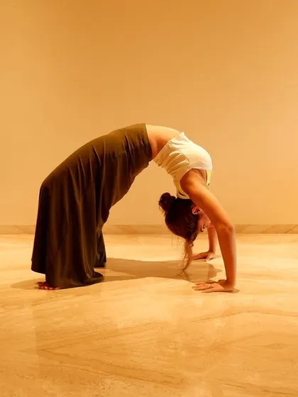 A deep backbend in the wheel pose. This is an advanced yoga posture that demonstrates incredible flexibility and strength, essential for a dancer's body.