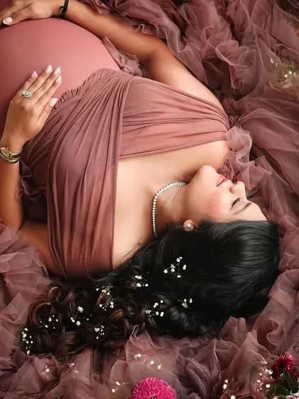 An artistic overhead shot of a mother-to-be surrounded by flowers and a sea of dusty rose tulle, creating a truly magical image.
