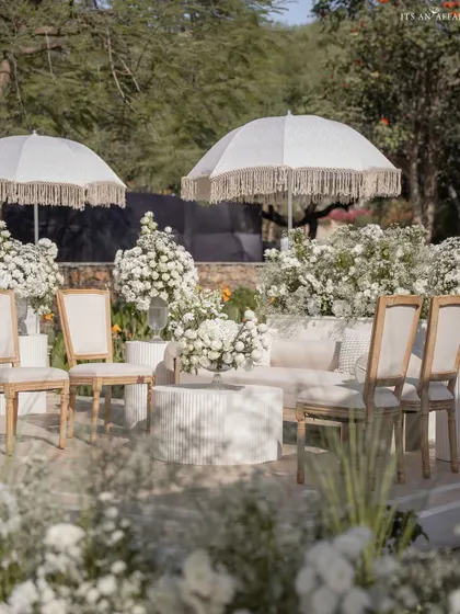 A chic lounge area at the lakeside Anand Karaj, with all-white furniture and fringed umbrellas providing a comfortable space for guests to relax.
