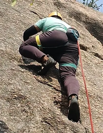 A participant practices footwork and balance on a granite slab during a top-rope climb.