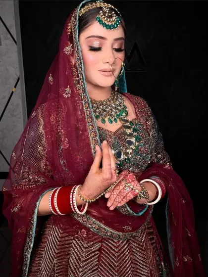 Our stunning bride in a deep maroon lehenga, adorned with a heavy polki and emerald set.