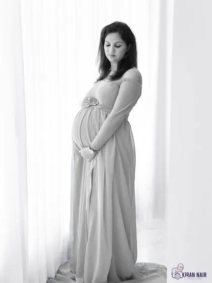A contemplative black and white portrait. The simple elegance of the gown and the soft lighting create a peaceful and beautiful image.