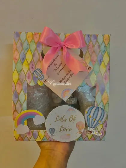 This colorful hamper combines a hot air balloon and rainbow theme. The gift box includes a scented candle, a butterfly-themed soap, and handmade chocolates.