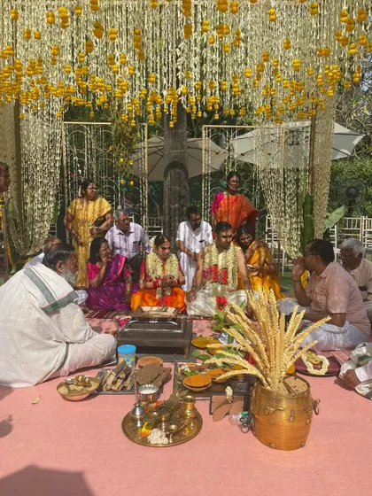A South Indian wedding ceremony in progress, with the couple seated under a breathtaking ceiling of jasmine and marigold strings.
