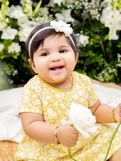 A sweet baby girl holding a flower, captured in timeless black and white.