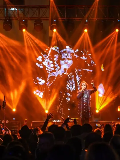 Bathed in orange light, our vocalist connects with the audience. A powerful shot from our NYE 2026 performance, highlighting the grand scale of the event.