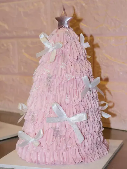 Another angle of our pretty pink Christmas tree cake, showing off the textured frosting and delicate bow details.
