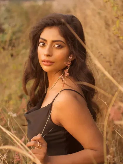 A direct and engaging portrait from the same field session. The subject holds a piece of grass, adding a natural, interactive element to the shot.