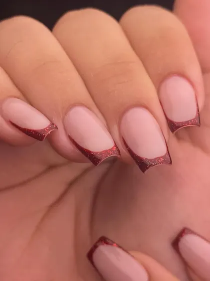 Simple, chic, and a little bit sparkly. This is a modern French manicure with a deep red glitter tip, giving the classic style a festive and glamorous feel. The curved smile line is sharp and precise.