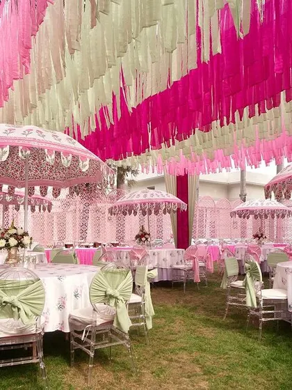 A wide view of the pink and mint green Mehendi, showing the beautiful interplay of colors in the drapes, umbrellas, and table settings.