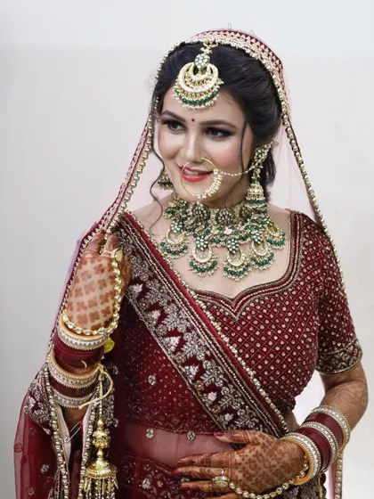 A happy bride showing off her complete rental set, including the green meenakari choker, matching jhumkas, nath, and maang tikka.