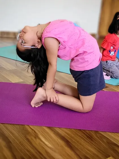 A young girl practices Ustrasana, or Camel Pose, a wonderful heart opening backbend that improves spinal flexibility.