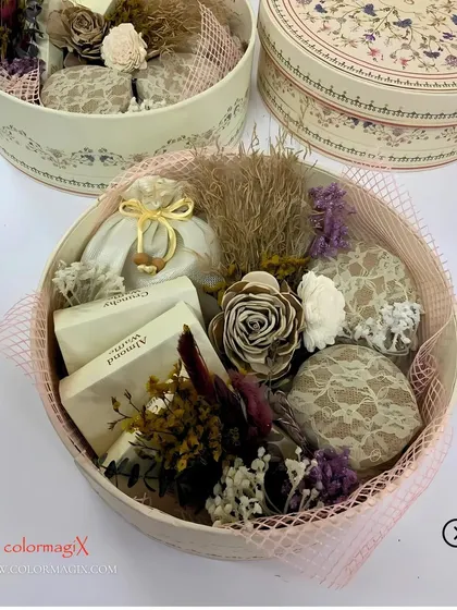 A close-up of our round wedding favor box, filled with gourmet treats and decorated with dried flowers. The design is both rustic and sophisticated, ideal for modern weddings.