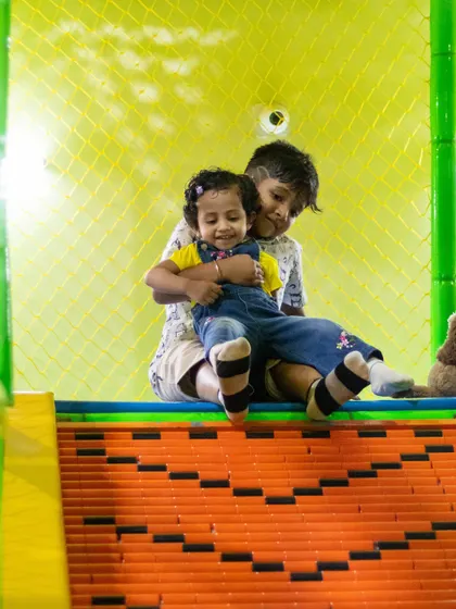 A sweet moment of sibling bonding at the top of our slide. Our play area is a great place for brothers and sisters to play together.