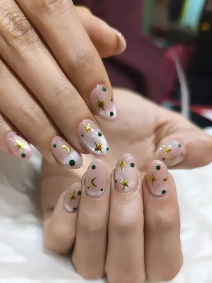 A celestial-themed design featuring gold moons and stars over a sheer, shimmery base with dark green polka dots.