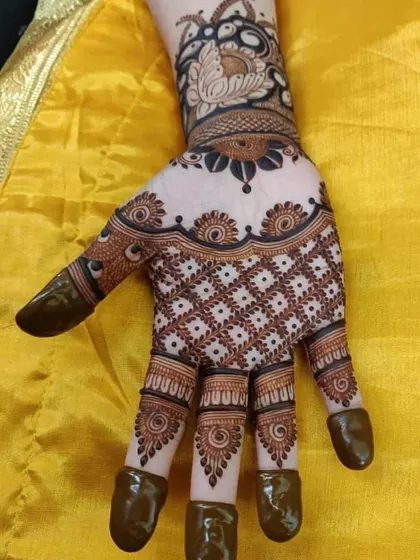 A beautiful back-of-hand design with a 'jaal' pattern and a bold floral cuff at the wrist. The fingertips are fully covered for a dark, traditional stain.