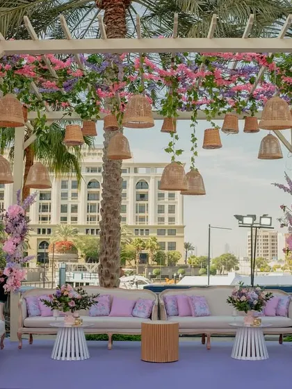 A beautiful lounge area for the Bridgerton Mehendi, featuring a pergola adorned with hanging baskets and florals, offering guests a comfortable and stylish place to relax.