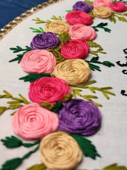 A detail shot of another custom embroidery piece with a heartfelt quote, "my heart beats only for you," surrounded by colorful hand-stitched roses.