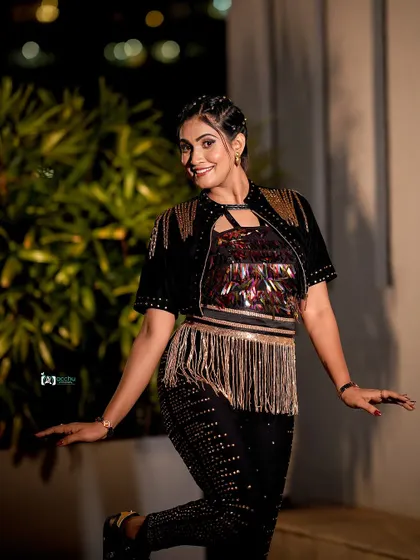 This playful pose captures the fun and energy of the event. The fringe and sequin details on the outfit add texture and movement to this dynamic nighttime shot.