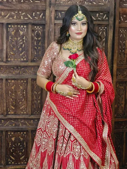 A classic red bridal lehenga paired with a gold and green Kundan jewellery set. The contrast between the red outfit and green beads is a timeless choice.