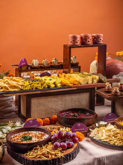 A rustic and earthy grazing table setup with wooden and slate platters. This spread features a variety of Indian snacks and dips, perfect for a traditional celebration with a modern aesthetic.