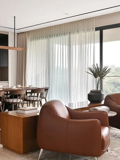 We designed this open-plan living and dining area to feel airy, warm, and welcoming. The large windows connect the space to the lush greenery outside, creating a sanctuary of laidback luxury in this Bengaluru apartment.