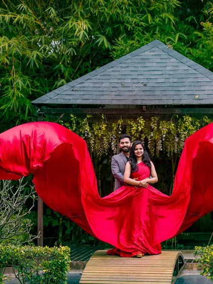 A slightly different angle of the "wing" pose, showing more of the garden path. The red gown's fabric seems to float in the air, creating a magical effect.