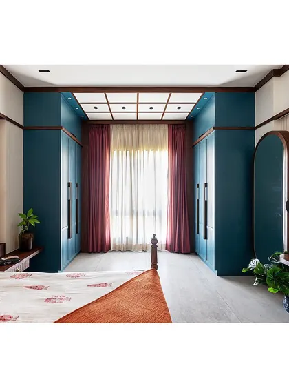 This wide shot shows the full layout of the bedroom, including the 'his and hers' wardrobes that frame the window, creating a beautiful and functional focal point.