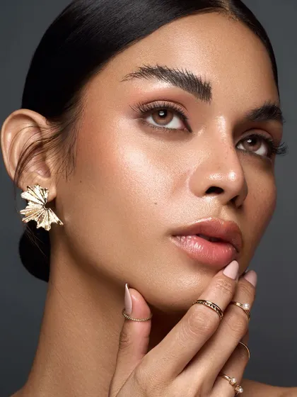 A similar frame that shows the versatility in posing, focusing on the elegant hand gesture and the soft, dewy finish of the makeup.