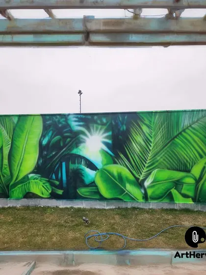 A stunning outdoor mural of a sunlit jungle, painted in Faridabad. The use of spray paint creates a soft, glowing effect, making the forest seem to come alive.