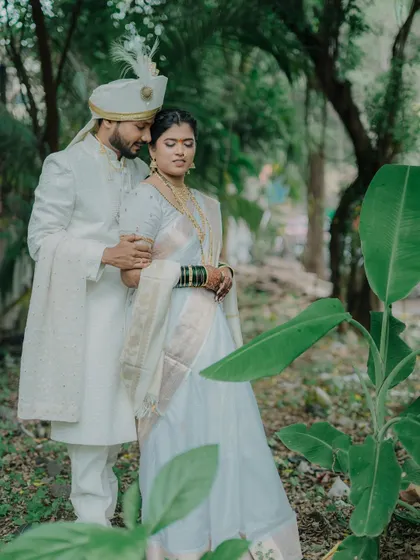 A classic portrait of the couple in a lush, green setting. The groom's arm around the bride conveys a sense of protection and love.