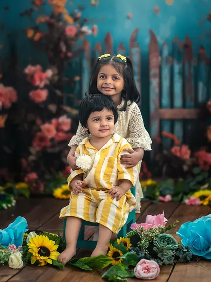 A sweet portrait of a brother and sister in our floral garden setup. The older sister's gentle embrace is a testament to their loving bond.