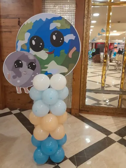 A cute balloon pillar with Earth and Moon character cutouts. These small touches help fill the space and reinforce the party's theme.