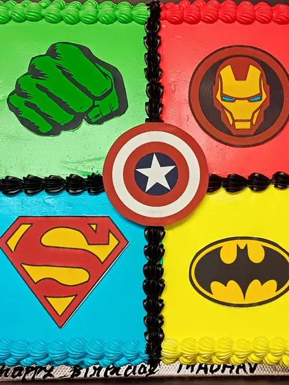 A superhero sheet cake for an Avengers fan, featuring the logos of Hulk, Iron Man, Superman, and Batman.