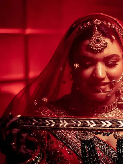 A classic bridal portrait with a red veil, using shadows to create a sense of timeless elegance.