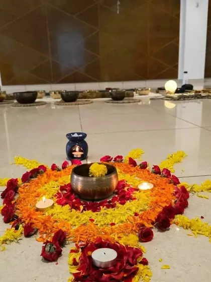 A close-up of the beautiful setup for a sound healing session, featuring a flower mandala, candles, and a singing bowl.