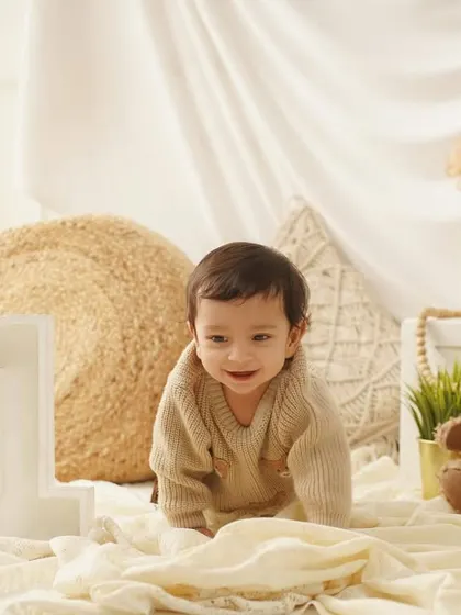 A candid shot of a baby boy crawling towards the camera during his cozy, teddy-bear themed first birthday photoshoot.
