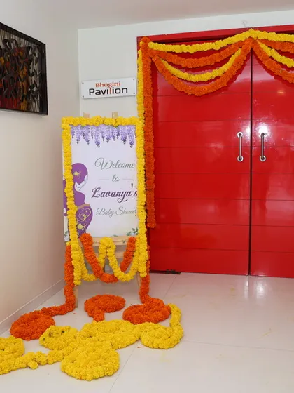 A wider view of the baby shower entrance, showing the welcome sign and marigold garlands decorating the main doors of the venue.