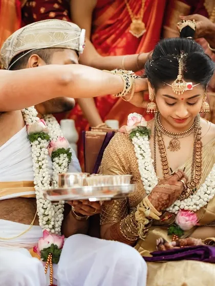 A close-up of the Mangalyam ceremony. This shot highlights the significance of the ritual, focusing on the groom securing the sacred necklace for his bride.