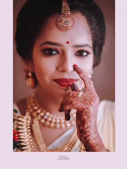 A stunning close-up bridal portrait, focusing on the bride's expressive eyes, red lipstick, and intricate henna design.
